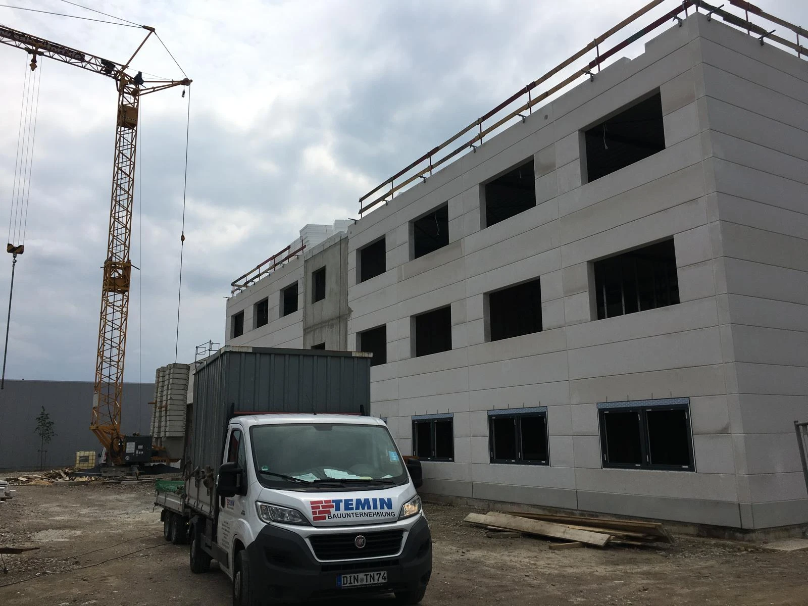 Mehrgeschossiger Rohbau mit Fensteröffnungen, Baukran und Temin-Fahrzeug