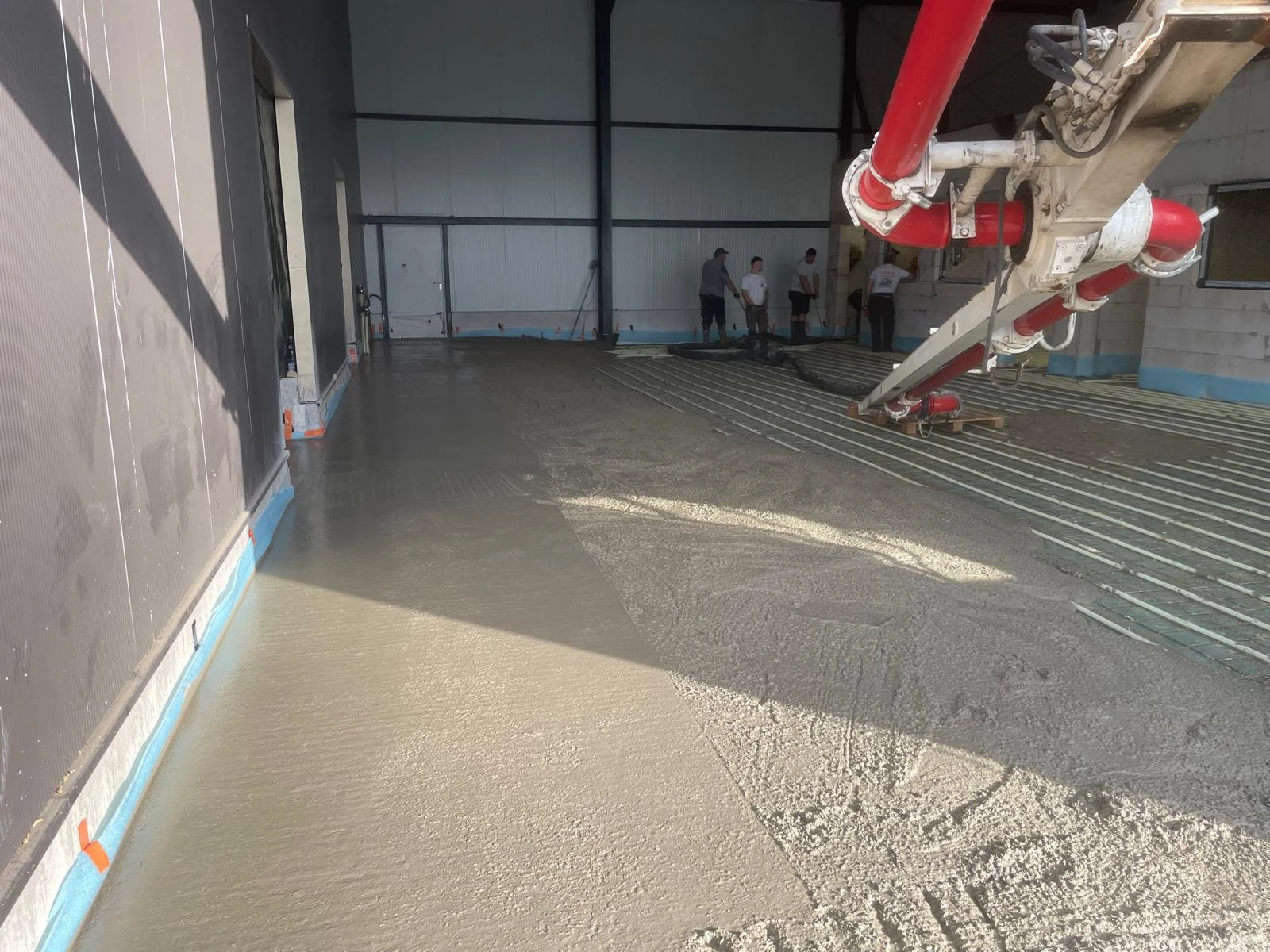 Betonpumpe beim Einbringen eines Bodens in einem Halleninnenraum