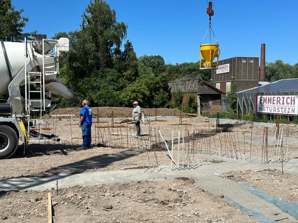 Betonmischer und Krankübel bei Fundamentarbeiten mit herausragender Bewehrung